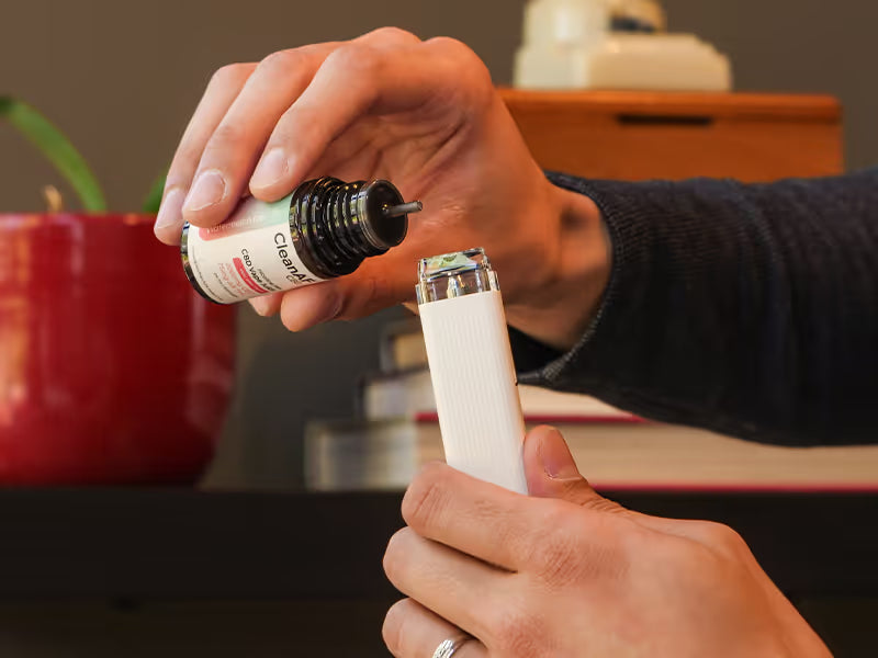 hands with THC vape juice filling a refillable vape pen