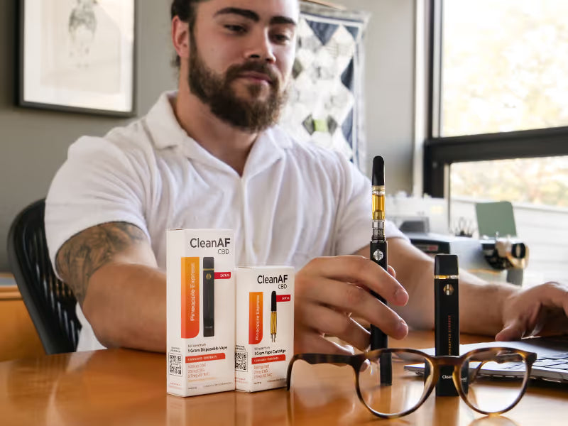 man at desk with THC vape cartridges